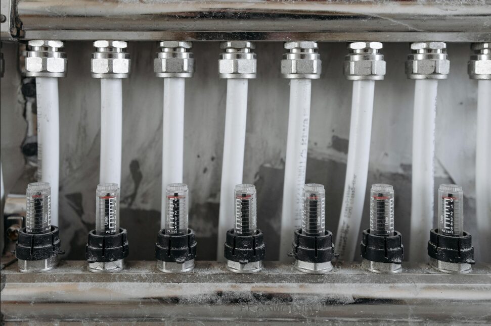 Close-up of underfloor heating manifold with flow meters and connected pipes
