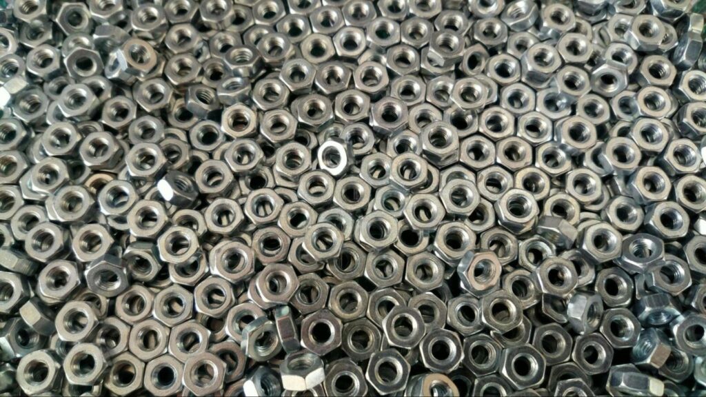 Close-up of metal hex nuts arranged in bulk, used for industrial and mechanical fastening applications