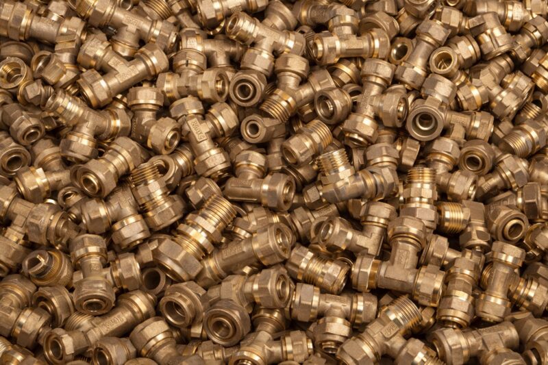 Bulk brass compression fittings and plumbing connectors stacked together
